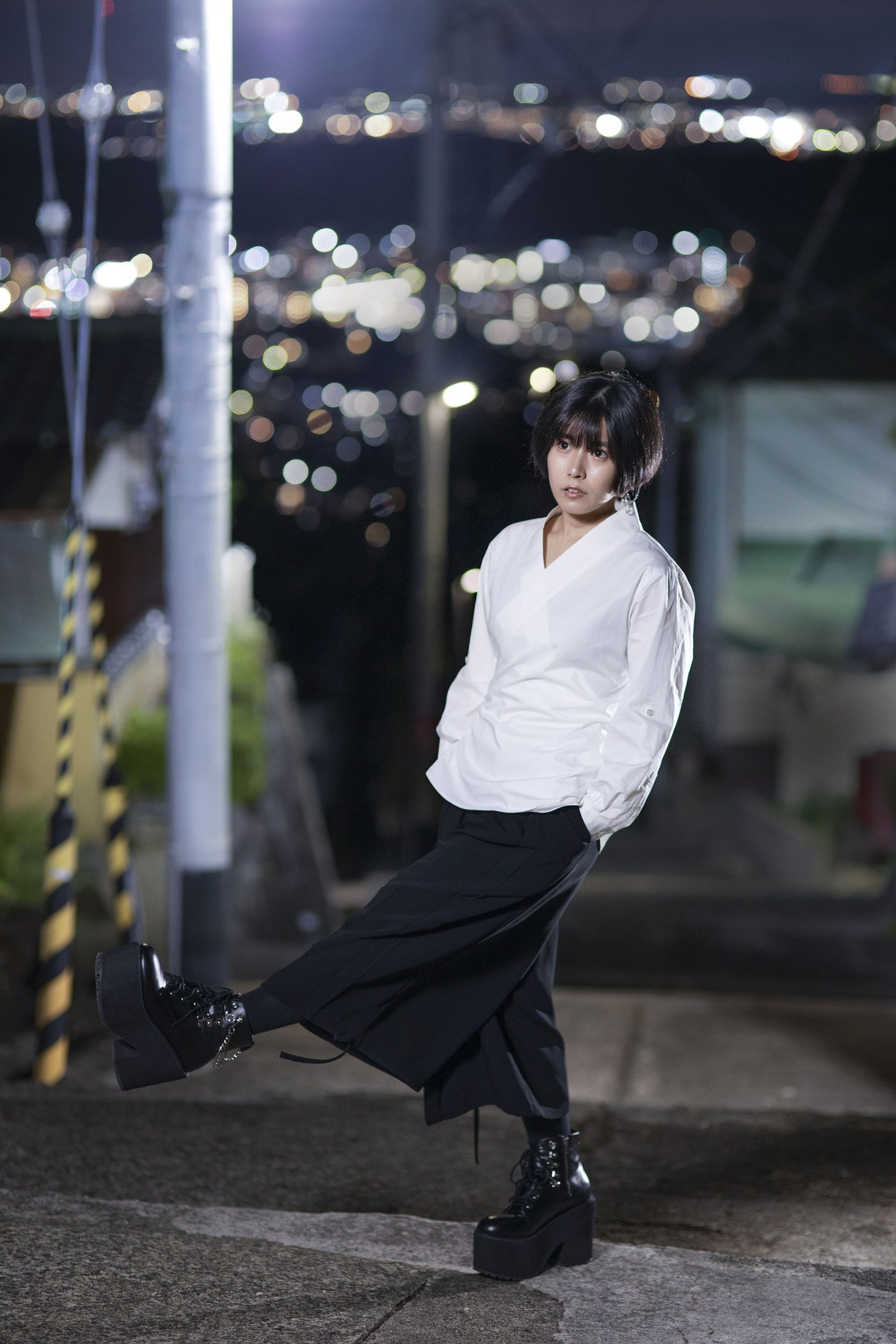 白いシャツにSamurai Mode Pantsを合わせ、夜の街を歩く女性