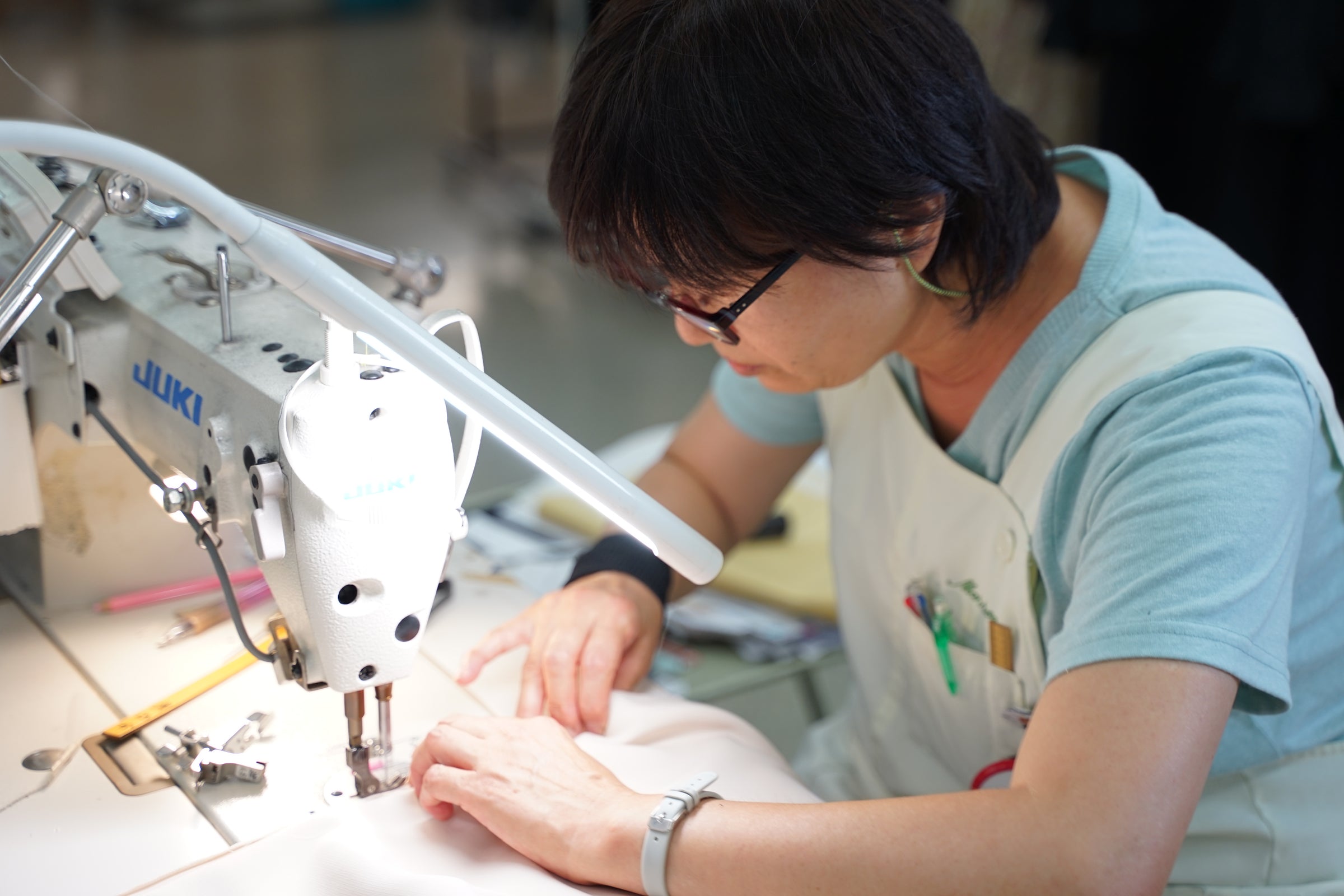 日本の縫製職人がミシンに向かい、一着を縫い上げている手元