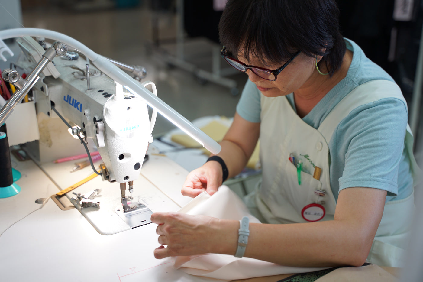 一着を縫う職人の手とミシン