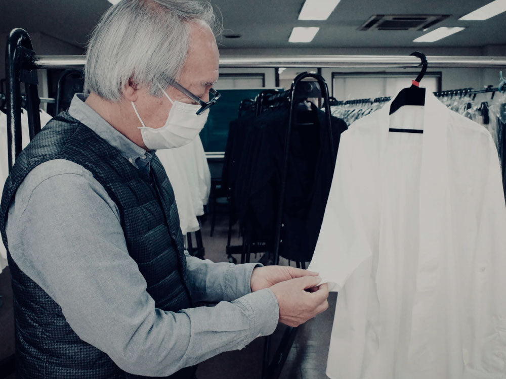 The hands and machine of the artisan sewing a single garment